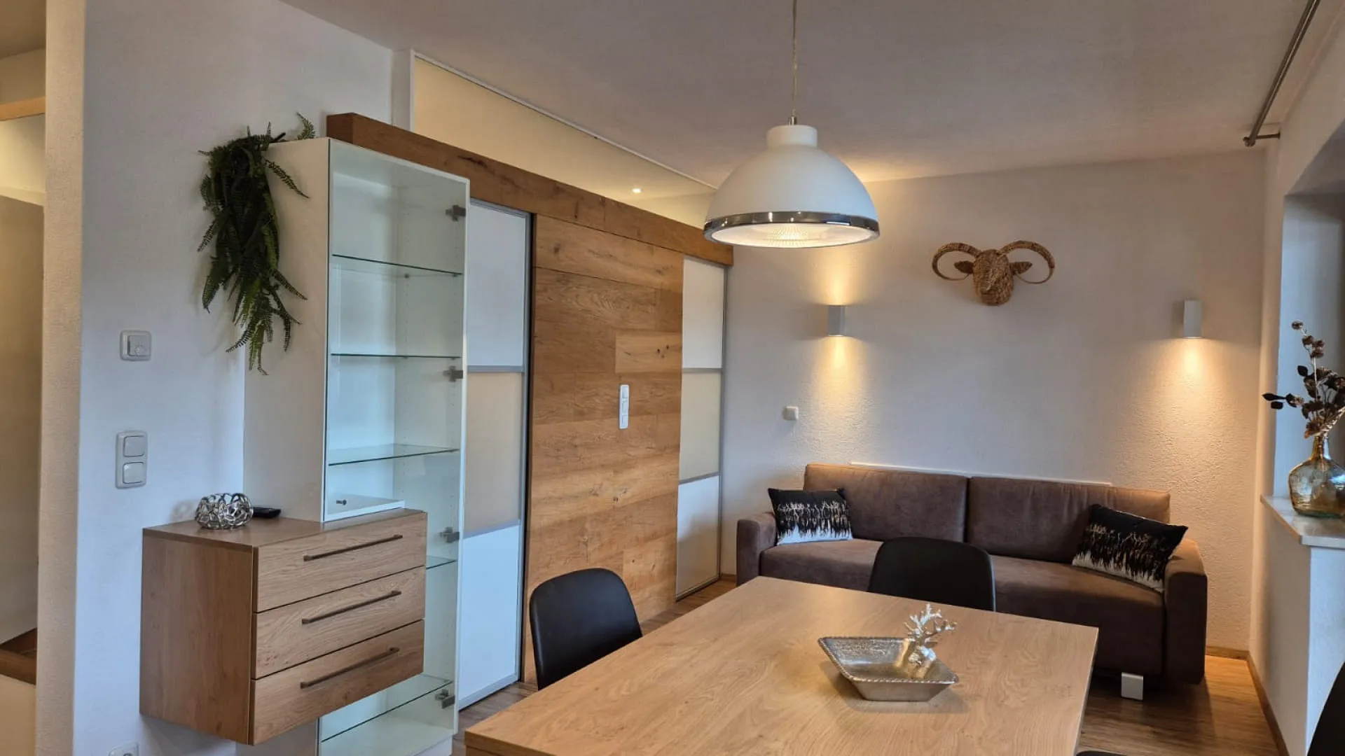 Wohnzimmer mit einem Holztisch, einer Couch und einer Glasvitrine